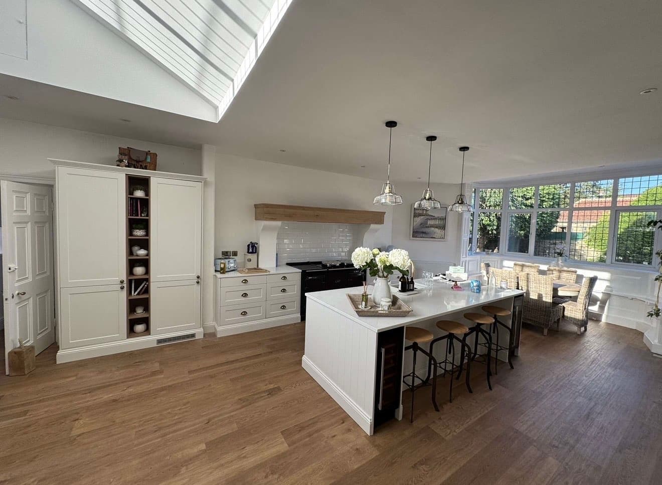 Open-plan kitchen extension with a vaulted roof lantern, kitchen island with bar seating and a dining area beyond, built by 4orty Construction