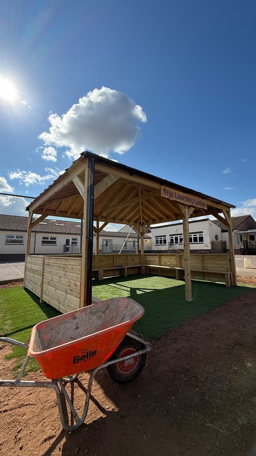 The Learning Lodge, a bespoke timber-framed outdoor shelter at a school, with pitched shingled roof, exposed timber frame and a sign reading 'The Learning Lodge'