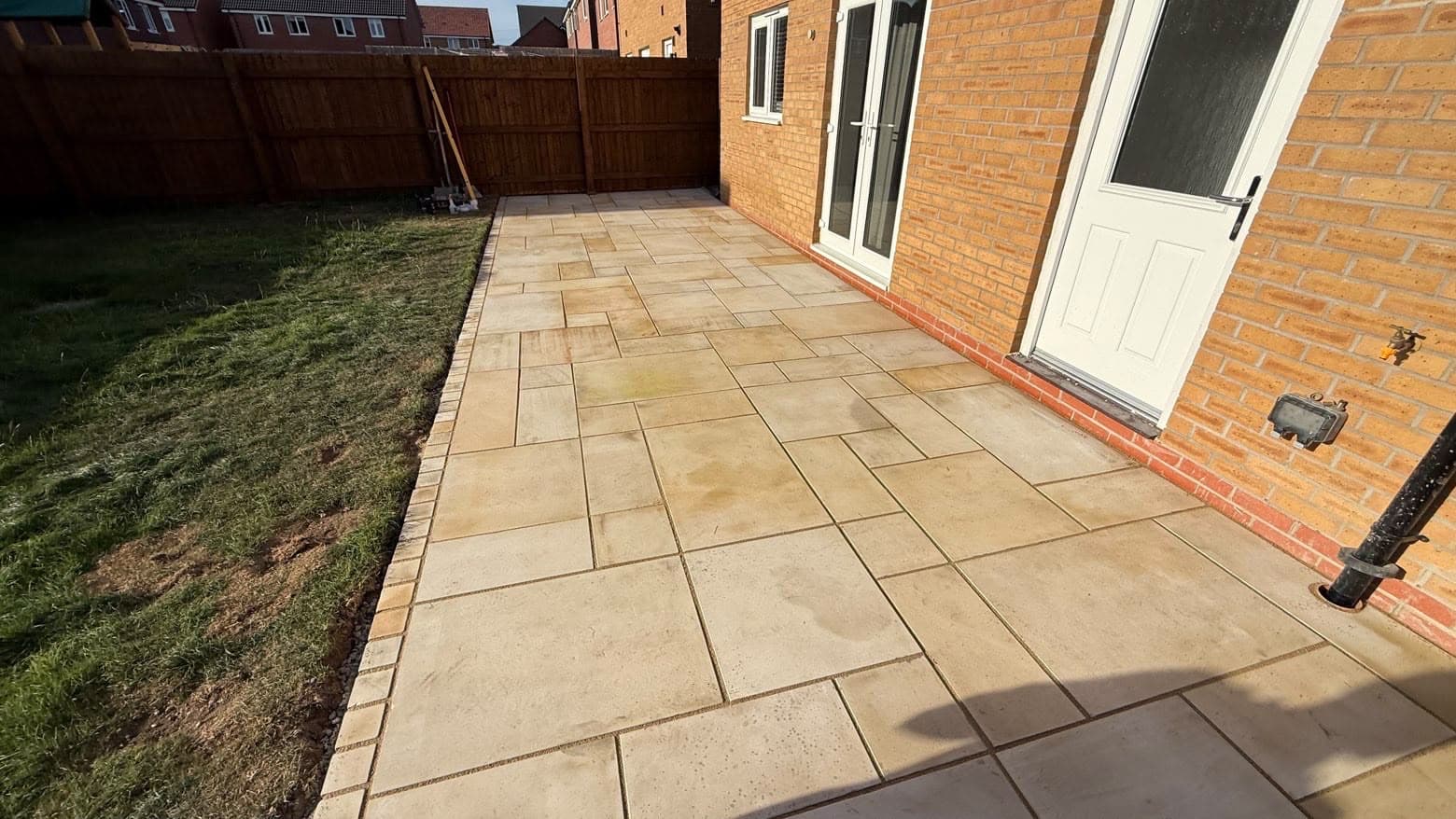 Paved patio installation in the rear garden of a new-build brick house