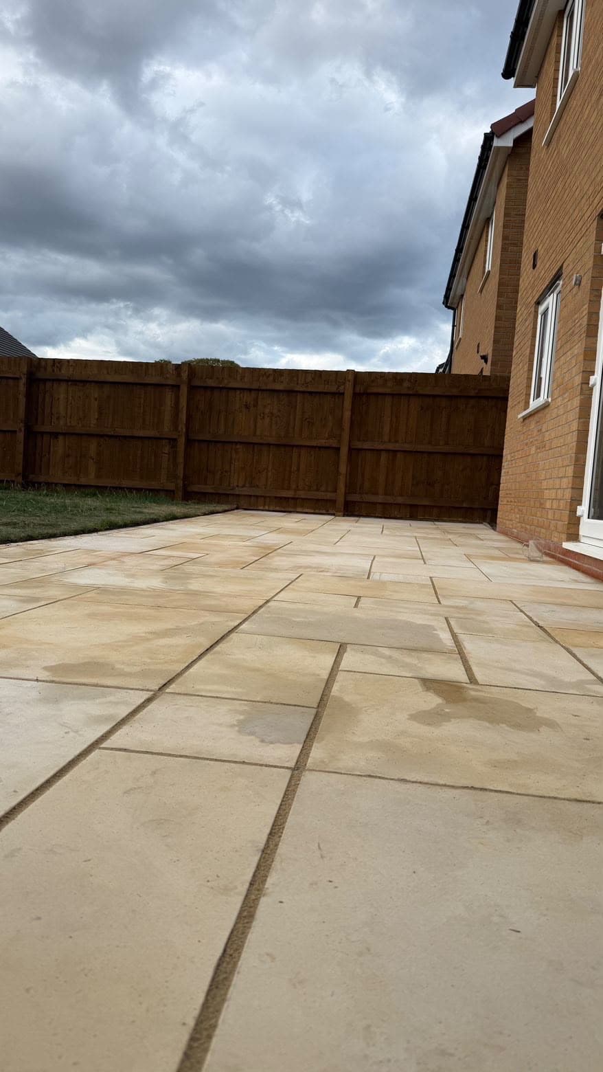 Patio under a dramatic cloudy sky, rear garden of a new-build brick house